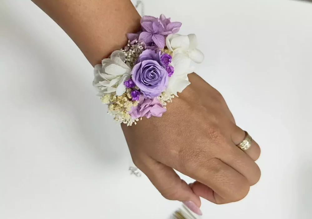 Pulsera para damas de honor con flores preservadas en tonos morados, blancos y beige. Un accesorio elegante y personalizado para bodas.