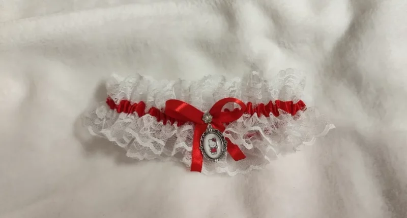 Liga de novia con encaje blanco, lazo rojo e incluye camafeo de Hello Kitty. Ajustable cualquier talla.