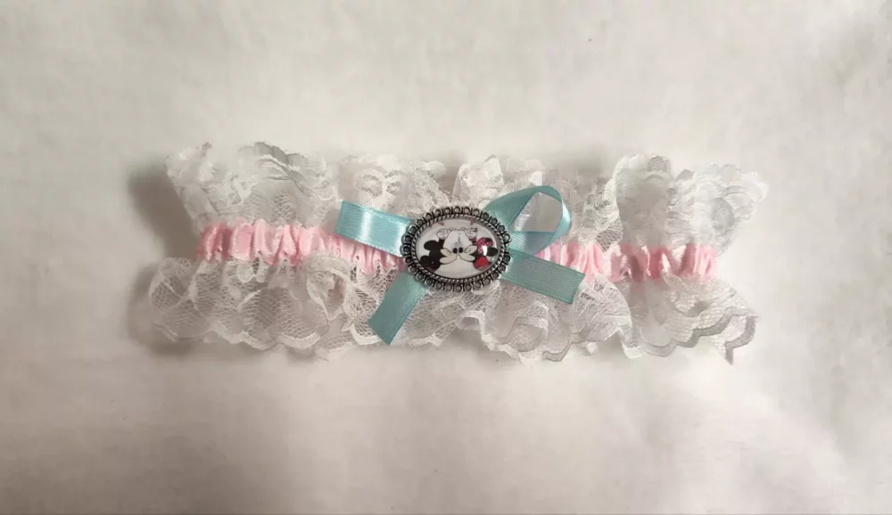 Liga de novia con encaje blanco, lazo rosa y camafeo de Minnie y Mickey.